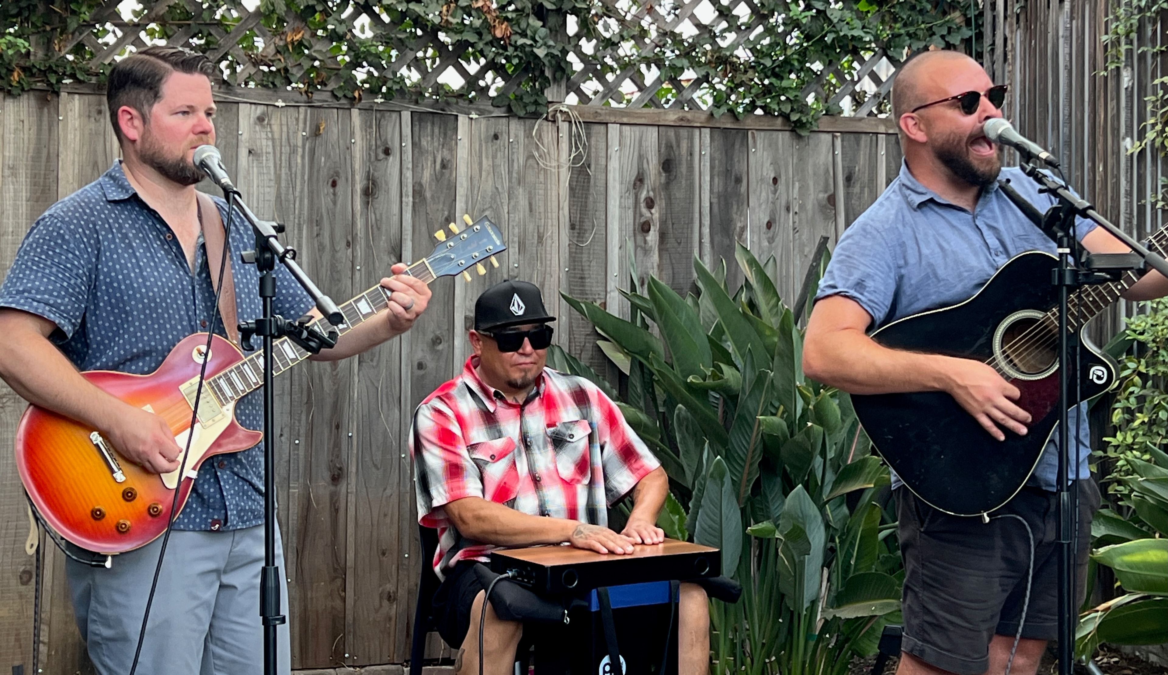 Three-piece band performing in a backyard garden